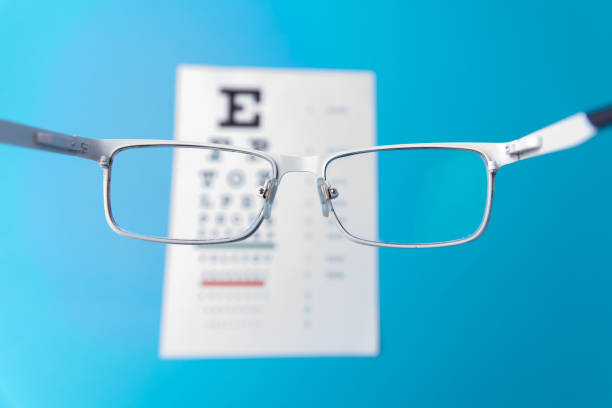 istock Hand-held glasses, view of the Snellen chart. Blue background 1182330810