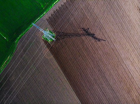 Drone shot of powerlines over agriculture fields during a day in summer