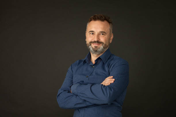 istock Studio portrait of a 50 year old bearded man in a blue shirt on a black background 1182336708