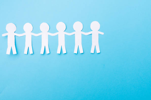 istock White paper people holding hands. Blue background. Place for text 1182338912