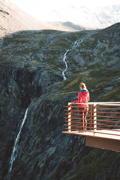 femme restant près de la barrière sur la plate-forme de point de vue trollstigen - norway snake street construction photos et images de collection