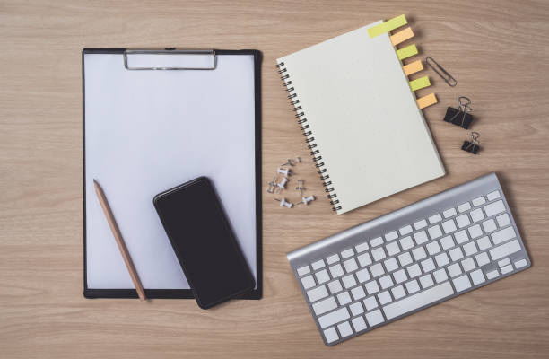 istock Workspace with diary or notebook and smart phone, clipboard, keyboard, pencil, sticky notes on wooden background 1182343149