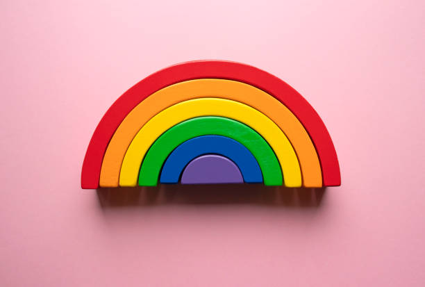 istock Bright wooden rainbow toy on a pink background - creative flat lay composition 1182343814