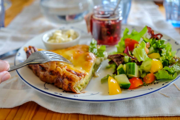 Close up shot of quiche lorraine lunch meal with raspberry jam and leaf salad