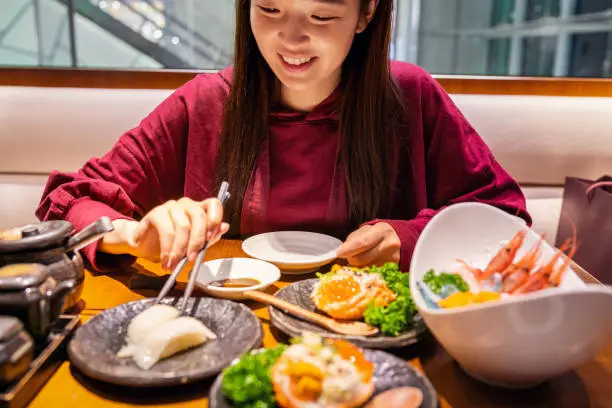 Photo of Cheerful Asian woman dining in a Japanese restaurant