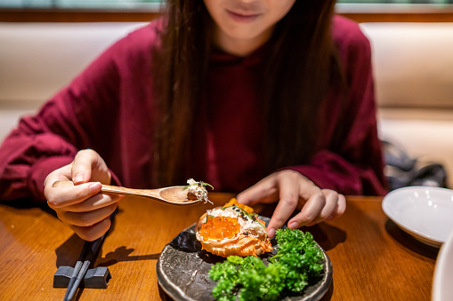 Young woman enjoying a crab sushi in a Japanese restaurant.