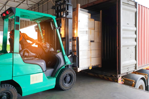 istock Forklift driver loading goods pallet into the truck container, freight industry warehouse logistics and transport 1182359406