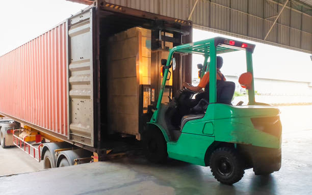 autista di carrelli elevatori che carica pallet merci nel contenitore del camion, logistica del magazzino del settore merci e trasporto - loading foto e immagini stock