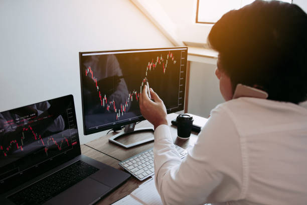 istock Agent trader man talking at telephone and checking business stock data on computer in office room. 1182360104