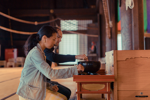 Multi-ethnic couple praying in a temple in Kyoto