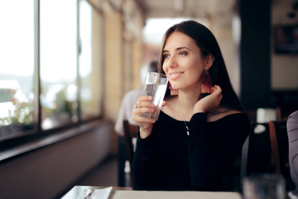 thirsty woman drinking a glass of water in a restaurant - fast water imagens e fotografias de stock