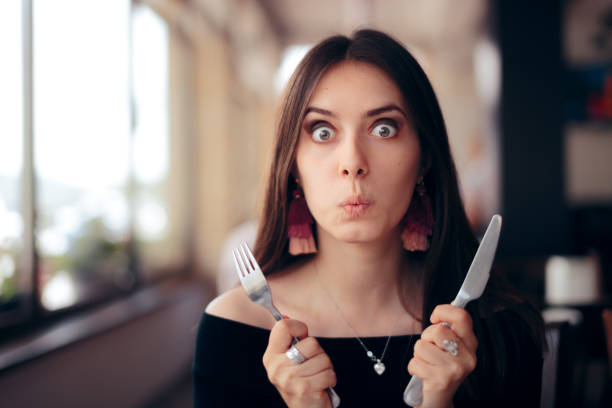 mujer hambrienta con cuchillo y tenedor listo para comer - sentarse a comer fotos fotografías e imágenes de stock