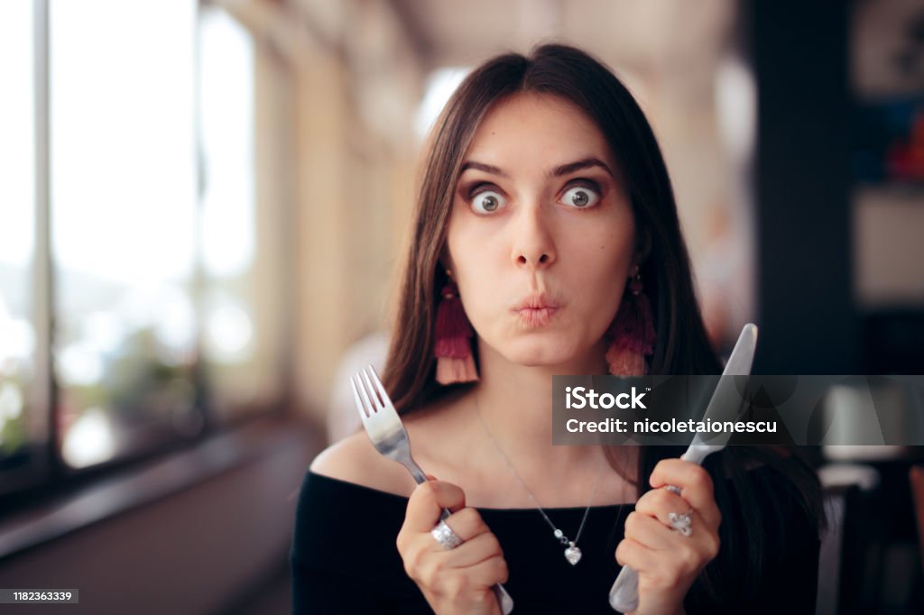 Hungry Woman with Knife and Fork Ready to Eat Greedy impatient girl waiting for her dish in a restaurant Hungry Stock Photo