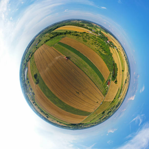 istock Aerial drone 360 degree spherical tiny planet view on red harvester during wheat field harvesting, collecting seeds, making dust cloud, driving forward 1182370067