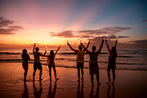 istock Big group of friends with bengal fires on beach 1182376108
