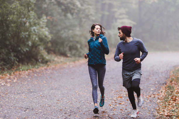 istock Athletic couple talking while running in misty forest. 1182377258