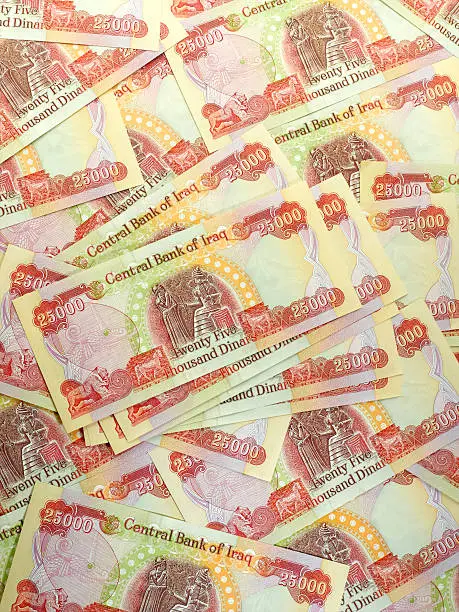 A large group of Iraqi 25,000 notes.  This is the English language side.  The reverse side of the bill is in Arabic.    This is the current day money in Iraq.  The currency with Saddam Hussain is outdated and no longer allowed.