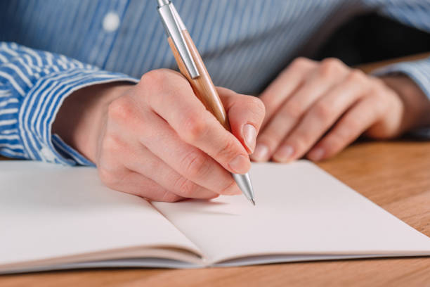 istock Beautiful Female hands write pen in a notebook of tasks and goals to work on a  table 1182379605