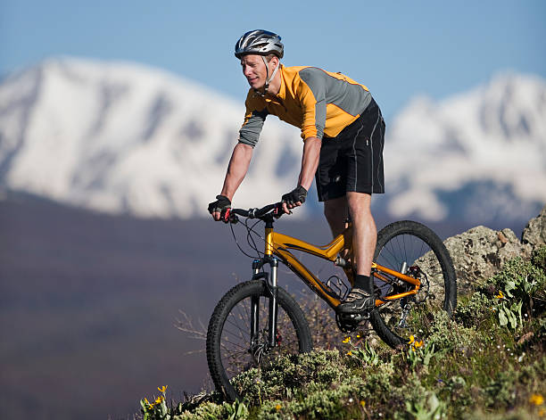 jovem homem, andar de bicicleta de montanha com neve coberta de montanhas no fundo - mountain biking colorado action cycling imagens e fotografias de stock