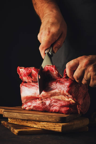 istock Male butcher cuts raw beef meat. 1182382337
