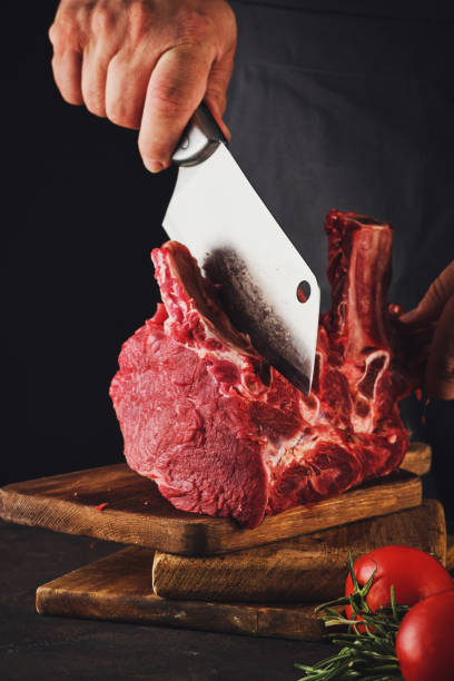 istock Male butcher cuts raw beef meat. 1182382480