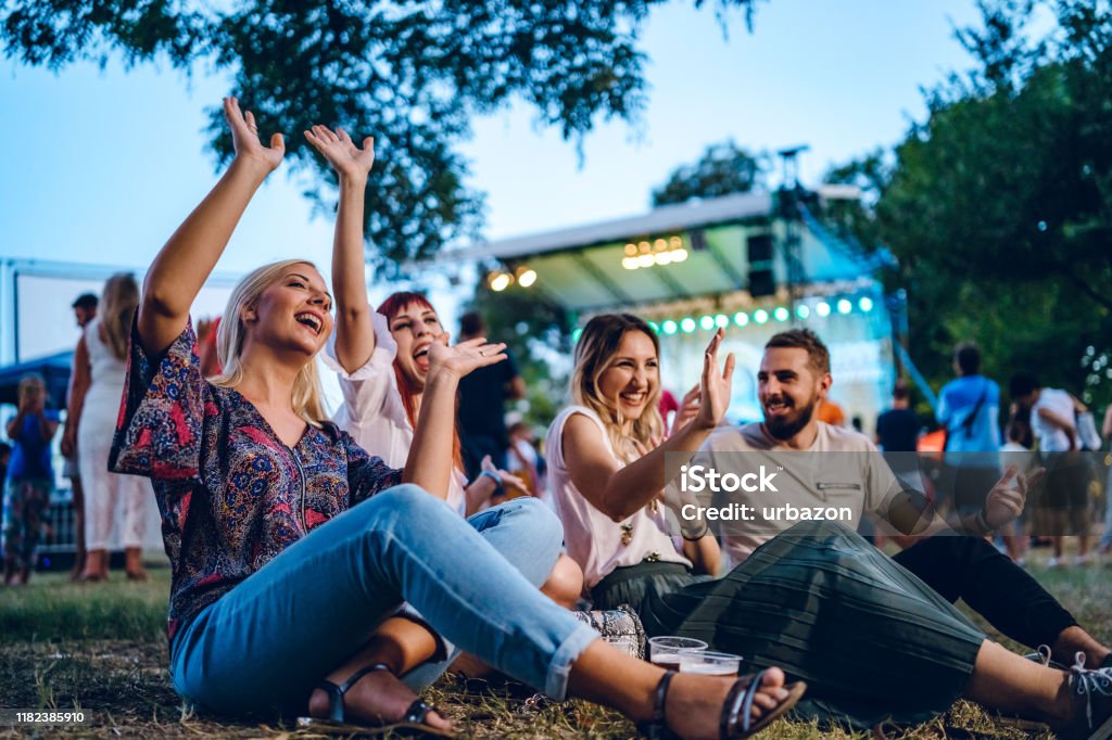 Group of friends on a music festival Group of young Caucasian friends on a music festival sitting in a grass together. Outdoors Stock Photo