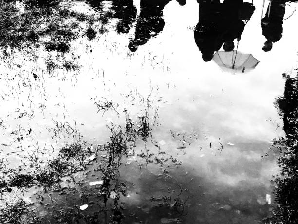 istock Silhouette of people reflex in a puddle in a raining day 1182385953