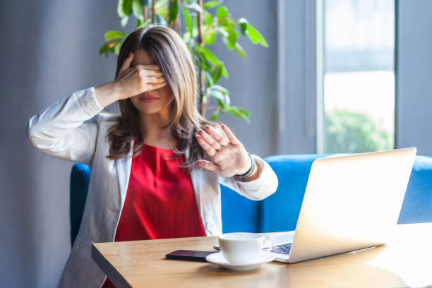 pare, eu não quero vê-lo. retrato da mulher nova tímida ou scared nos vidros que sentam-se, cobriu seus olhos com as mãos e não quer olhar a câmera. - fear hiding women office - fotografias e filmes do acervo