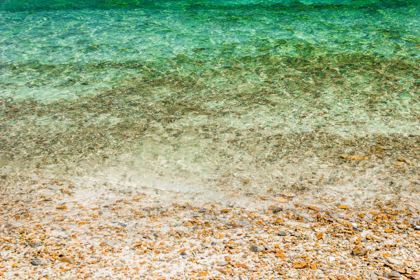 istock Soft waves with foam of water on pebbles and sandy beach. 1182388594