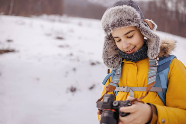 istock Boy in warm clothing checking photos on dslr camera 1182389227