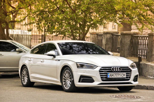 White Audi A5 parked in the city center against a tree stock photo