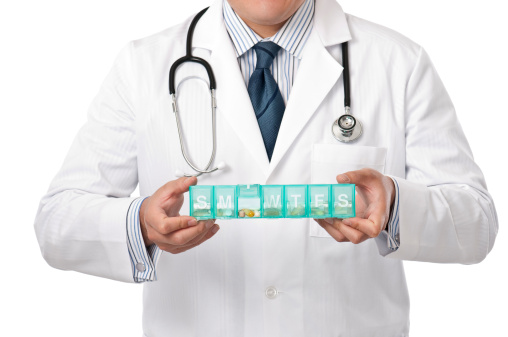 Young smiling male Asian Doctor holding pill box and with fish oil tablets.