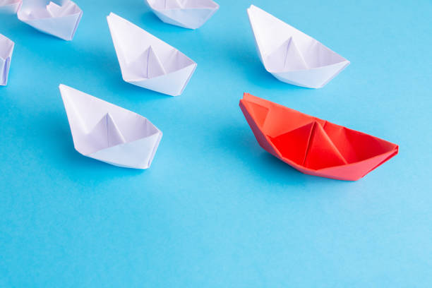 istock A red ship as a leader. White following it. Blue background 1182401861