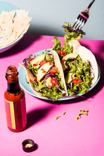 Healthy mixed salad on unwrapped tortilla, pink tabletop and blue background stock photo