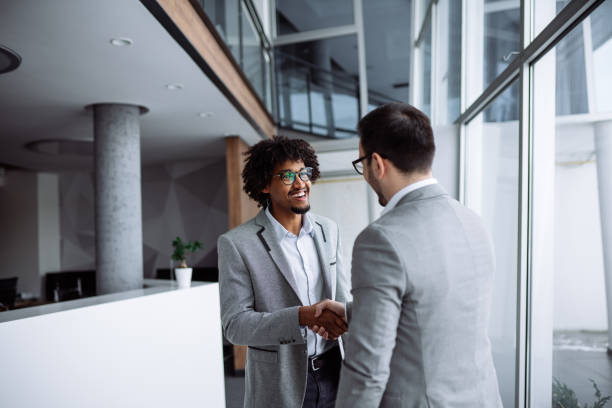 istock Diverse male employees shaking hands in hallway 1182402752