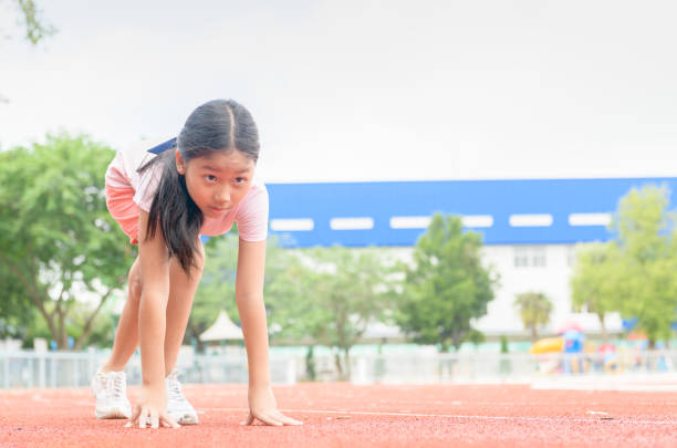 トラック上で実行する準備ができている位置に陽気なかわいい女の子、 - starting line competition running jogging ストックフォトと画像