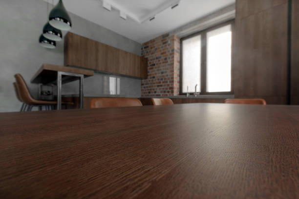 Out-of-focus kitchen background with focus on foreground area of wooden table for product placement. 