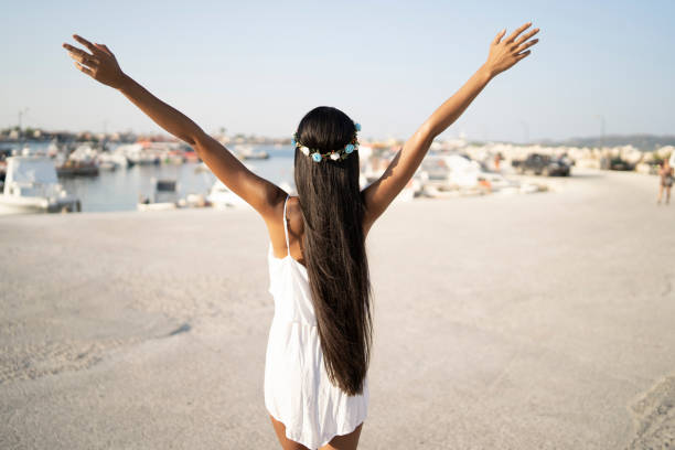 istock Young woman standing hands raised on beach and looking at sea 1182403018