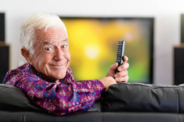 istock Smiling senior man with TV remote control 1182403480
