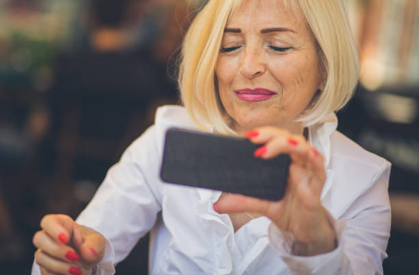 Staying within reach during her retirement thanks to mobile technology. Senior business woman in cafe using phone.