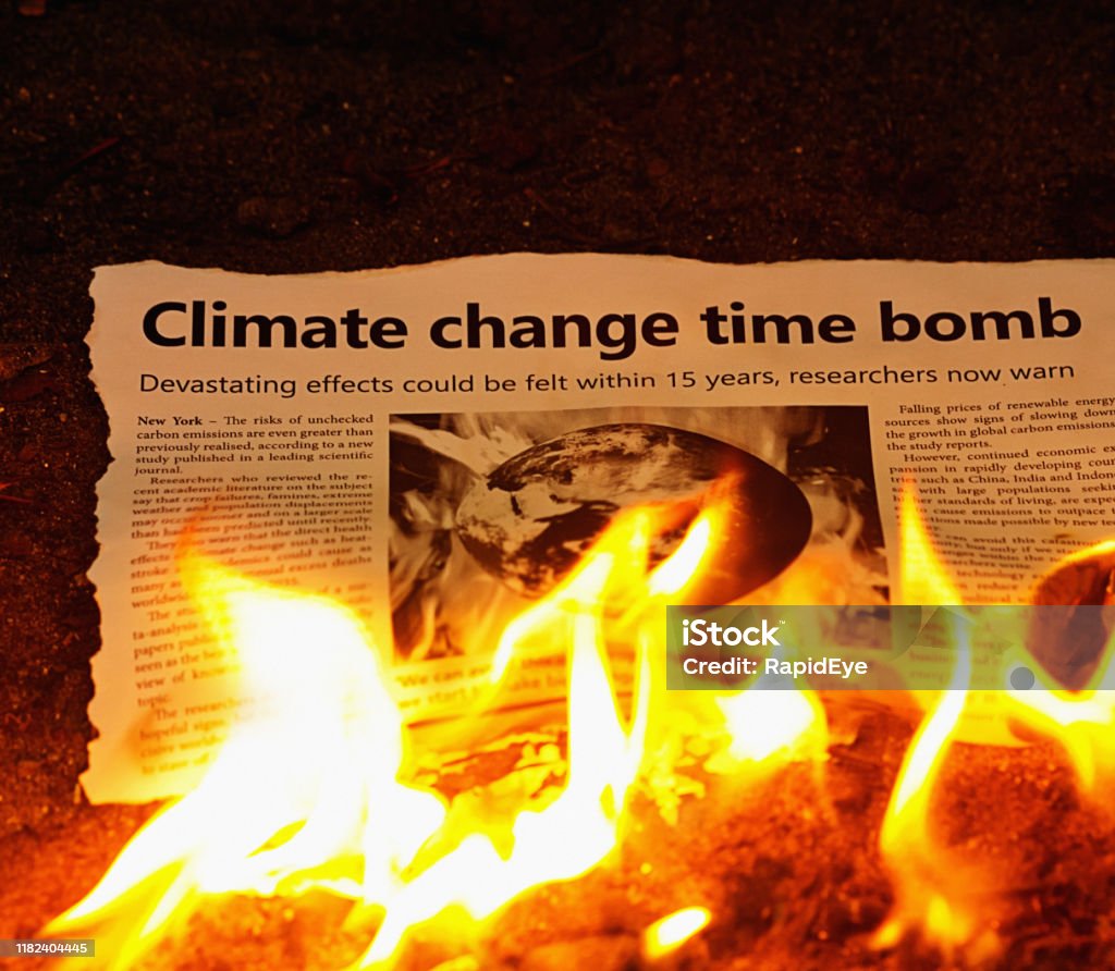 Climate change time bomb" headline on burning newspaper Please note: The design and text are my own creation. The illustration is a NASA earth image combined with a picture of my own. Thanks.

A newspaper with the headline "Climate change time bomb"  goes up in flames. Heat - Temperature Stock Photo