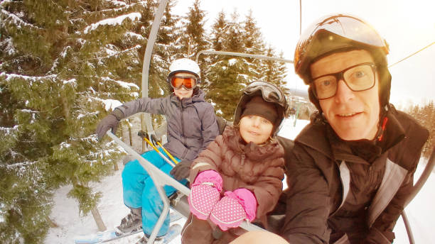 Father and kids taking selfie on ski lift