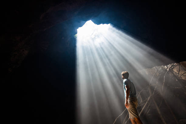 istock Carefree man looking at sunbeam entering the cave. 1182410017