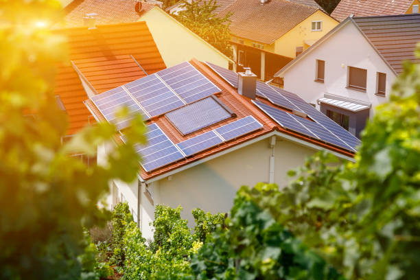 Solar panels on the tiled roof of the building in the sun. Top view through grape leaves. Selective focus. Solar panels on the tiled roof of the building in the sun. Top view through grape leaves. Selective focus. Blur rooftop solar stock pictures, royalty-free photos & images