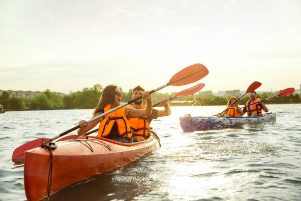 istock Happy friends kayaking on river with sunset on the background 1182411757
