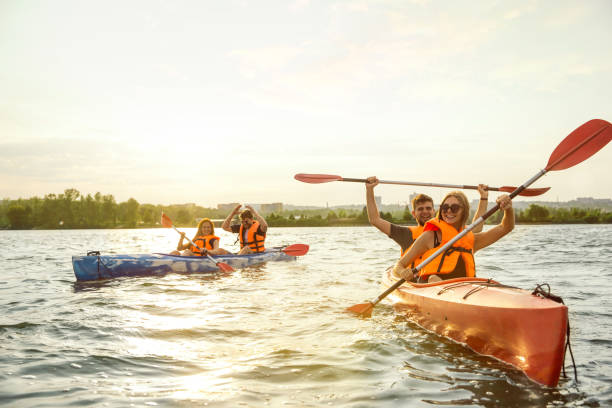 istock Happy friends kayaking on river with sunset on the background 1182411759