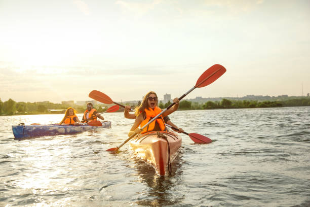 istock Happy friends kayaking on river with sunset on the background 1182411761