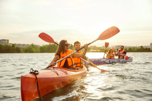 istock Happy friends kayaking on river with sunset on the background 1182411777