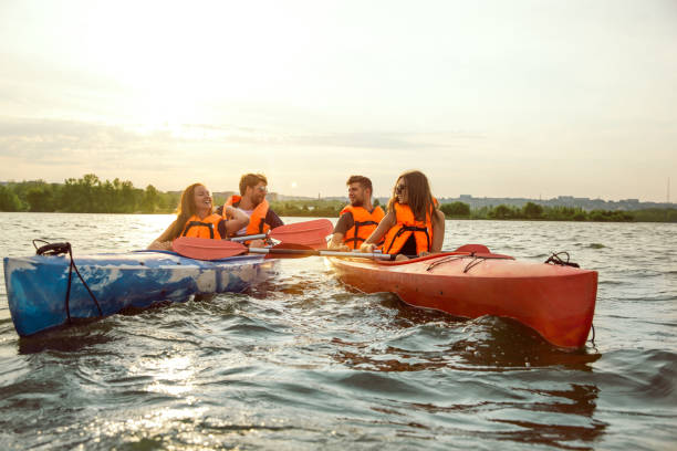 istock Happy friends kayaking on river with sunset on the background 1182411785