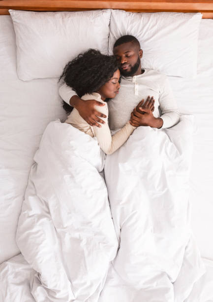 coppia di famiglia nera sdraiata e coccolata a letto, dormendo insieme. - couple affectionate relaxation high angle view foto e immagini stock